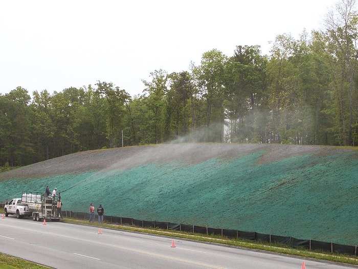 The reclamation process begins with an application of hydroseed. A mixture of seed and mulch that clings to the coarse rock and dirt below.