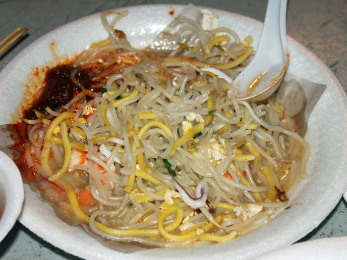 Fried Hokkien Mee is made with a combination of thick yellow egg noodles and rice vermicelli noodles which are cooked in a seafood broth and topped with shrimp, squid, pork belly, and lard. Singaporeans love to add chili sauce for an extra kick.