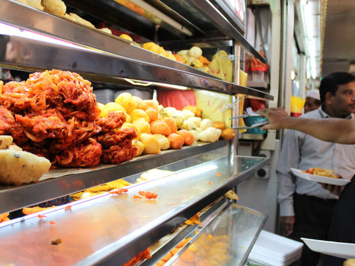 People help themselves to fried pakora (vegetables) and other fried Indian treats.