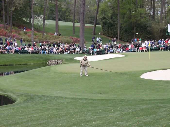 After Cabrera hit his sand shots, he had sand all over the green. These maintenance guys come out with this long bending black stick and sweep away all the sand making the greens green and smooth once again.