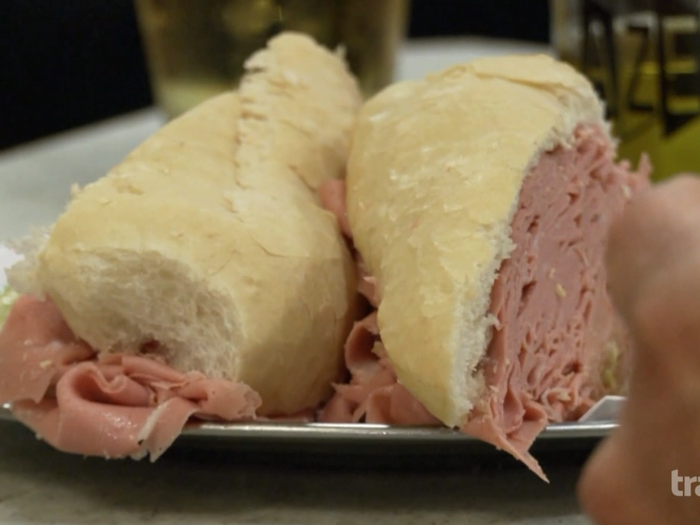 Next, Bourdain spots and orders a mortadella sandwich, which includes large heaps of sliced Italian sausage.