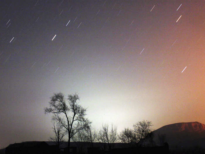 A long exposure photo shows star trails behind a tree in China.