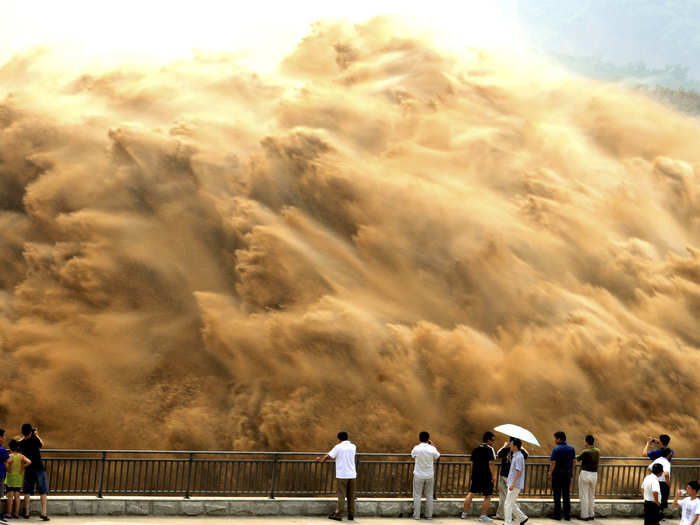 Visitors watch water gushing from the section of the Xiaolangdi Reservoir on the Yellow River, during a sand-washing operation.