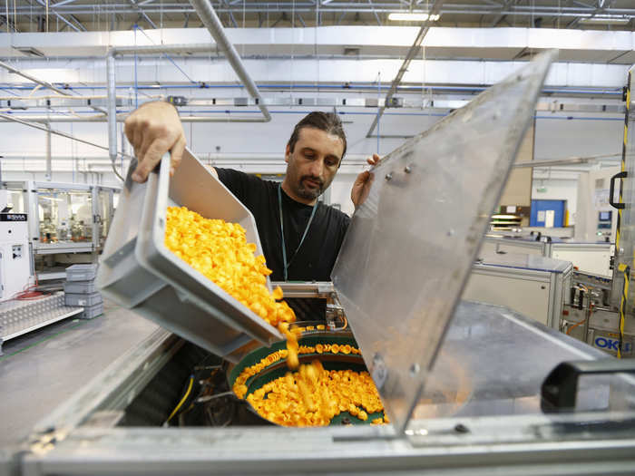 A worker pours hair pieces into an assembly machine. Workers pour pieces into the machines, where they are assembled.