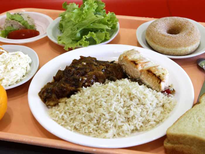 LAMBERSART, FRANCE: Another fancy lunch includes rice, salmon, ratatouille, a slice of bread, a salad with celery and carrots, an orange, and donut.