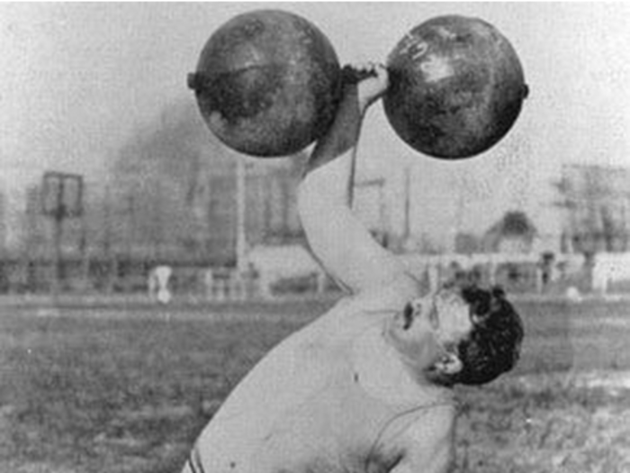 The Olympics that year also featured some events no longer held. These games were first and last to include the All-Around Dumbbell Contest. American Frederick Winters, shown struggling here, took the silver medal, losing to fellow American Oscar Paul Osthoff.