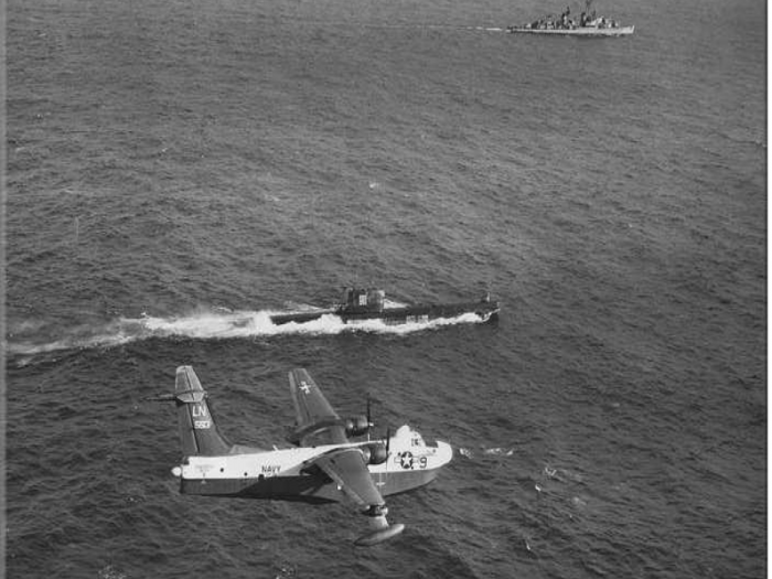 The Navy played a major role during the Cuban Missile Crisis, enforcing a blockade to prevent Soviet weapons deliveries to Cuba. This 1962 photo shows a Navy seaplane and destroyer ship shadowing a Soviet submarine.