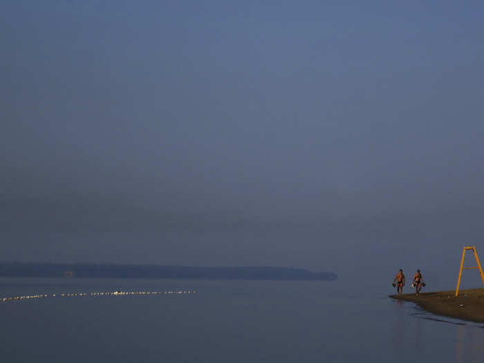 Swimmers walk along the beach.