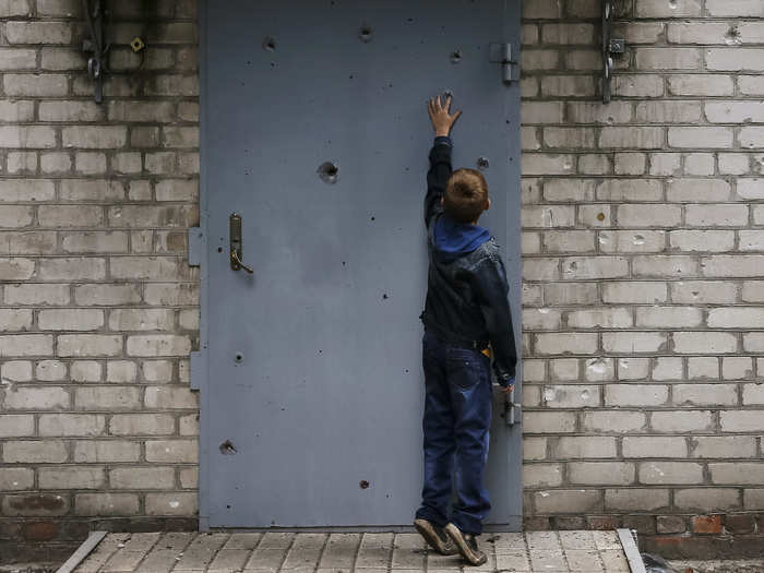 Here, a boy looks at a shrapnel hole in the door of a residential building in Slaviansk.