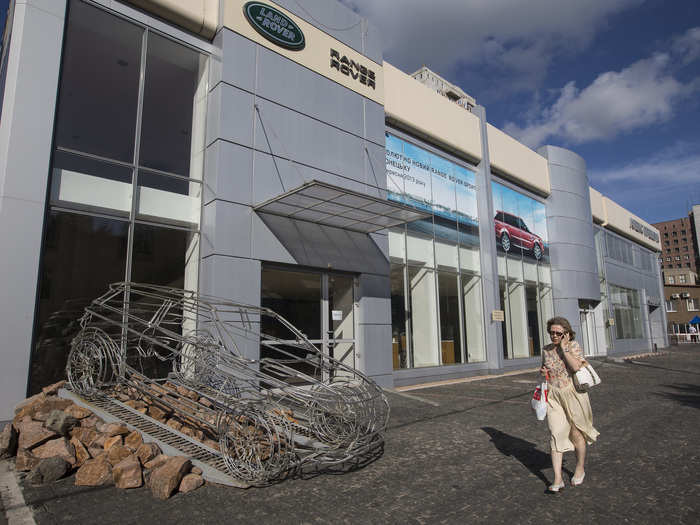 Business in Donetsk has fallen off drastically since the rebels took control. Here, a woman walks across an empty parking lot in front of a closed Land Rover showroom.