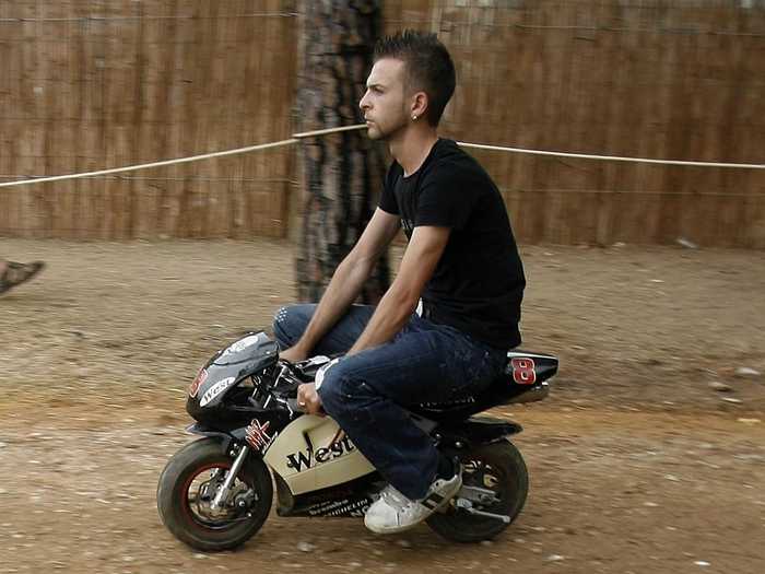 A man rides a tiny bike at a summer motorcycle rally in southern Portugal.