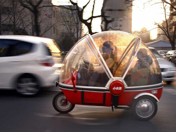 A woman and her son ride their bubble-shaped electric tricycle around Beijing.