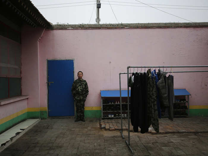 A young student stands outside the door to his dorm at Qide.