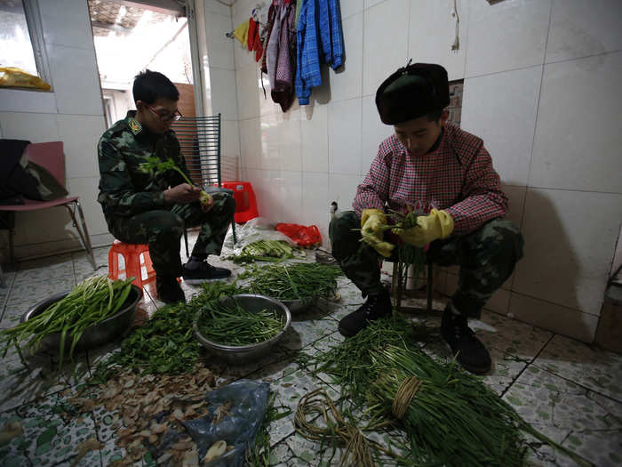 A pair of teenage boys learns how to prepare vegetables to be eaten.