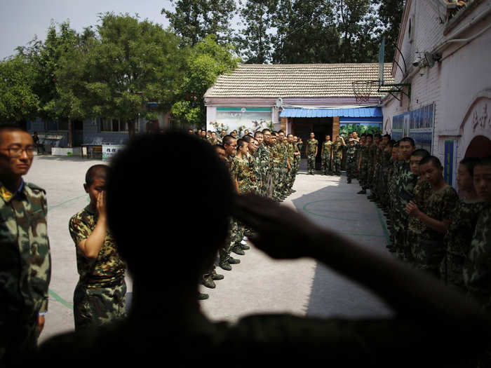 A student who has completed a six-month course salutes his classmates as he leaves Qide.