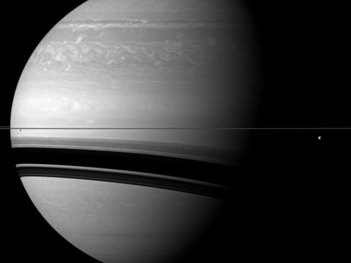 Saturn is enormous compared to its moons. Tethys is on the right side of the image below the rings, Enceladus is on the left side below the rings, and Pandora is barely visible on the left edge of the image right above the rings.