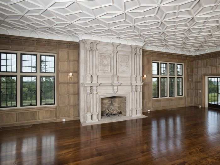 The 45-foot living room has paneled walls, an elegant limestone fireplace, and wide-board teak floors.