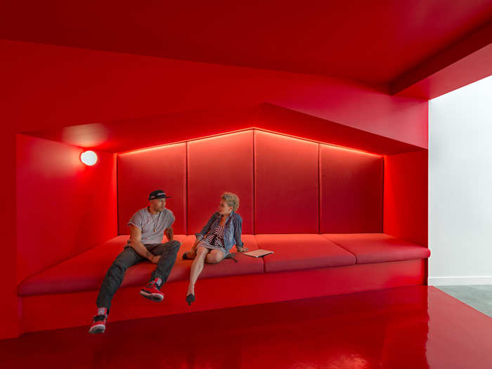 Stunningly bright red corridors link the working areas together. This hallway even has a couch built in.