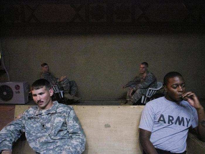 Specialist James Worster (left) and Sergeant Brandon Benjamin take a cigarette break while in the Baghdad ER. Two months after this photo was taken, Worster died of an overdose of a sedative, propofol. Drug abuse was widespread in the hospital unit.