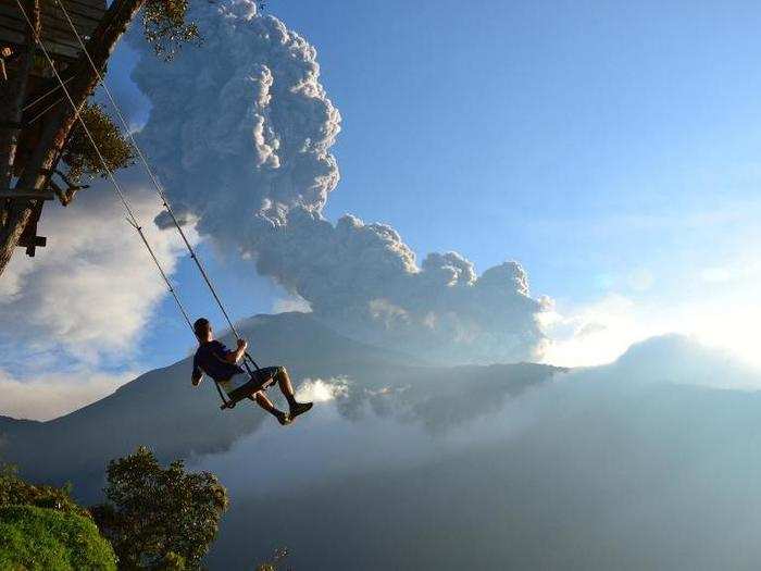 MERIT PRIZE: This "end-of-the-world" swing in Banos, Ecuador hangs over a deep abyss and is connected to a treehouse that is also a seismic monitoring station. In the background, an erupting Mount Tungurahua can be seen. Minutes after the photo was taken, the area was evacuated.