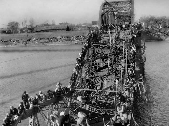 In this photo by Max Desfor that won the Prize in 1951, residents from Pyongyang, North Korea, and refugees from other areas crawl perilously over shattered girders of the city