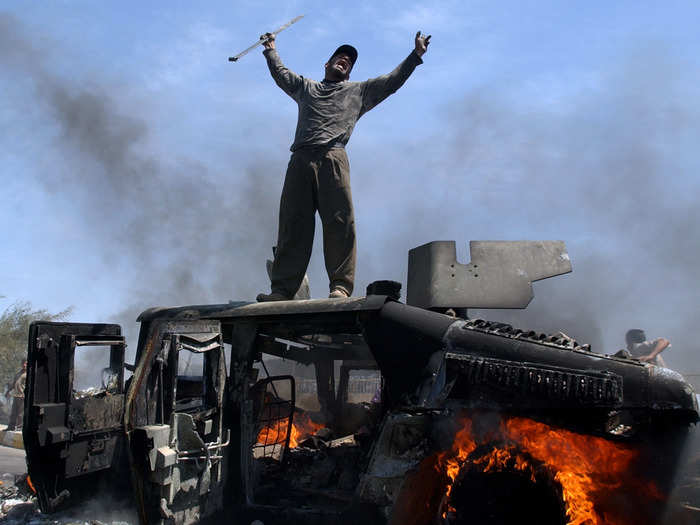 An Iraqi man celebrates atop of a burning U.S. Army Humvee in the northern part of Baghdad, Iraq. This photograph, taken by Muhammed Muheisen, was one in a portfolio of twenty taken by eleven different photographers throughout 2004 that won the Pulitzer Prize the following year.