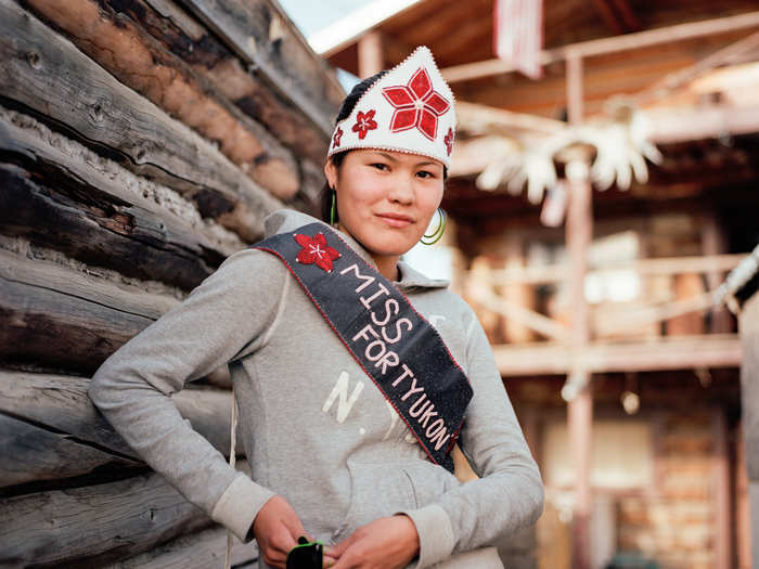 Standing outside her father’s multi-story log cabin in Fort Yukon, Alaska, Chasity Herbert is proud to appear in her newly won Miss Fort Yukon sash.