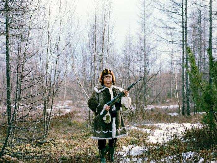 Maria Ivanova, seen here in traditional Yakut dress, is holding a rifle used for practice shooting in the forest after a family picnic in Zhigansk. There are over 500,000 Yakut people in the world today, with a vast majority of them living in Northern and Eastern Russia.