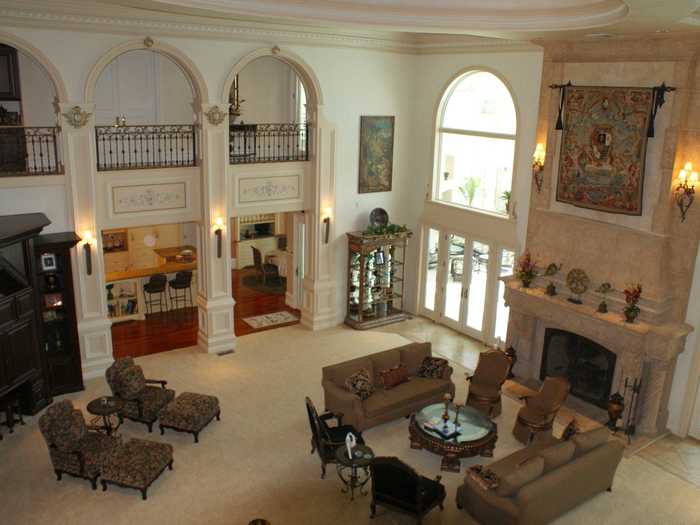 This is the upstairs view of the living room, which has large windows, arched entrance ways, and a fireplace.