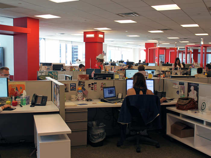 In the main room, more than 100 employees across departments work in an open-plan arrangement.