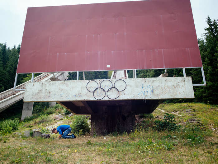 Here, we see the large wall that has been placed at the foot of the ski jumps which still bares the Olympics Rings insignia.