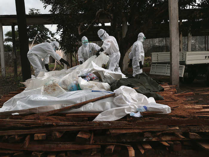 Many Liberians are convinced that people are dying of other causes. Many of the deceased are not tested before burial or cremation. Here, Liberian Ministry of Health workers unload the bodies of Ebola victims onto a funeral pyre.