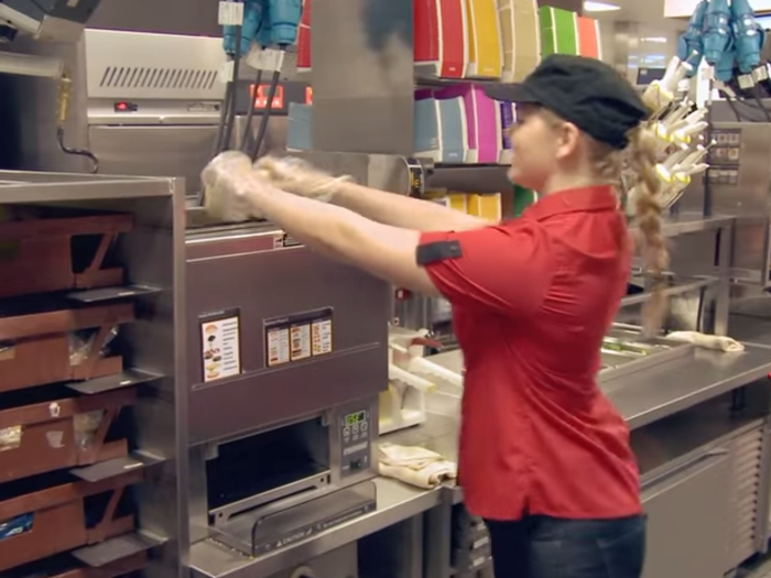 The buns are stored in the brown crates to the left in the image below. Geoghan is shown dropping a bun into the toaster.