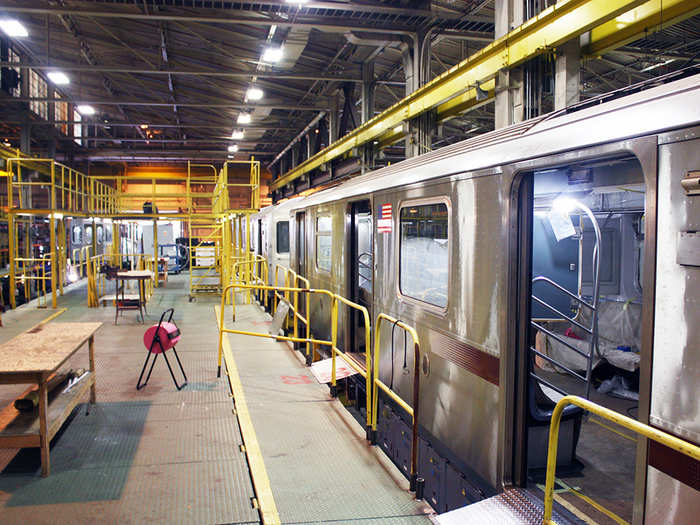 When they arrive, the cars are placed on a long track in the center of the facility, where they are worked on. You can see that the work platform is two-tiered, allowing workers to install equipment, like air conditioning, in the roof compartment.