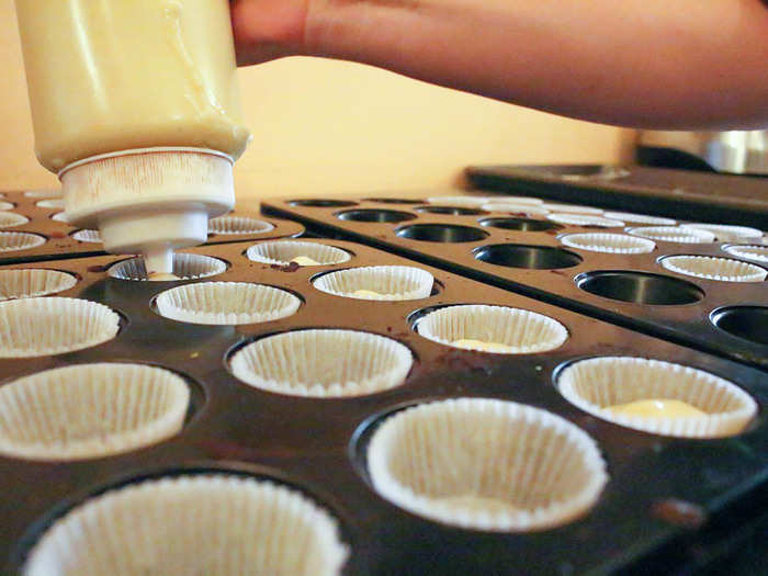 She pours the batter into a squeeze bottle and rapid-fire fills rows of mini cupcake liners. Prohibition Bakery bakes between 3,000 and 4,000 cupcakes a week.