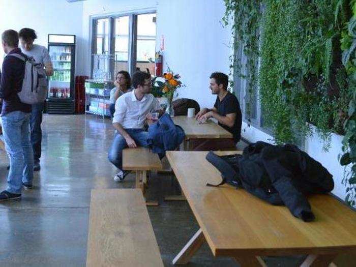 Next to the kitchen is a big, cafeteria-style space for people to eat and hang out. More live wall-plants create a vibrant ambiance.