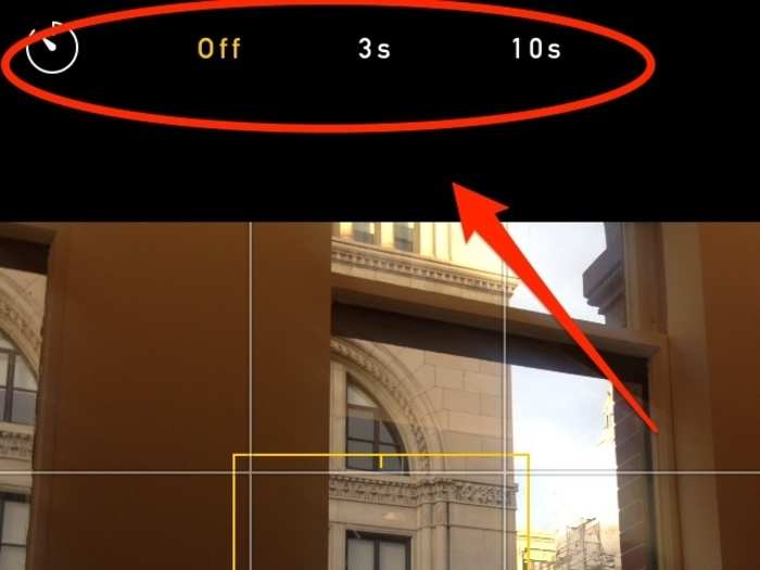Take advantage of the timer in iOS 8. By tapping on the clock-shaped icon above the viewfinder, you can choose to set a timer for either 3 or 10 seconds.