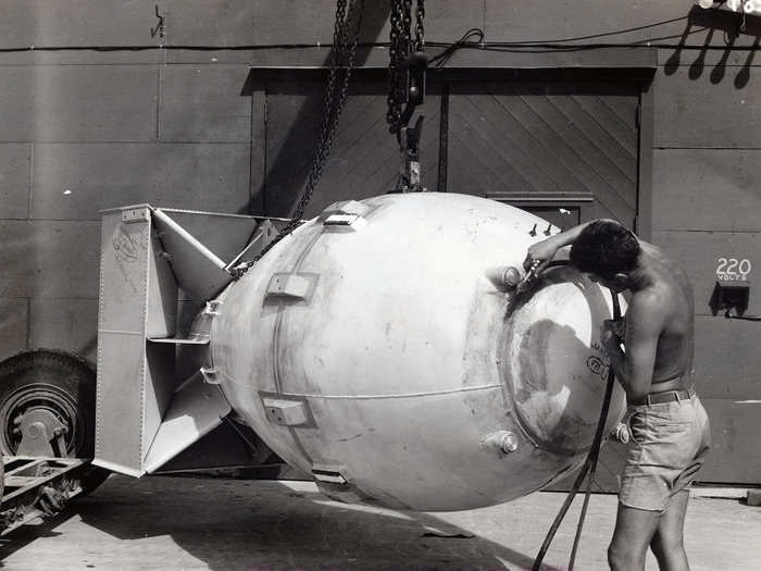 A technician applies sealant and putty to the crevices of "Fat Man," a final preparation to make sure the environment inside the bomb would be stable enough to create a full impact once it detonated.