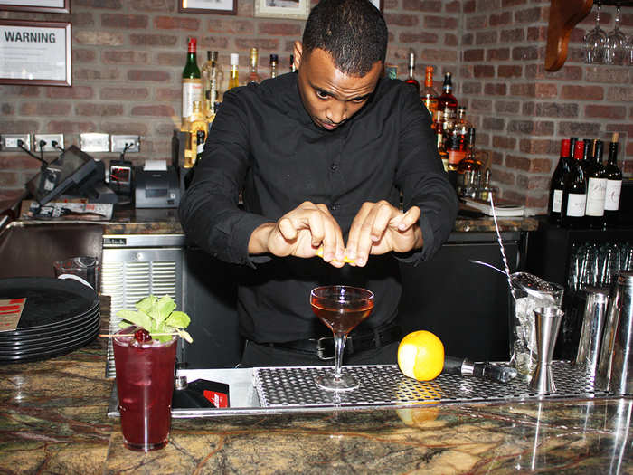 Here, head bartender Terrence Laboy makes a Lower Manhattan, a craft cocktail with whiskey, vermouth, and orange peel. To his right is a Coney Collins, another popular drink with vodka, blackberries, lemon, and mint.