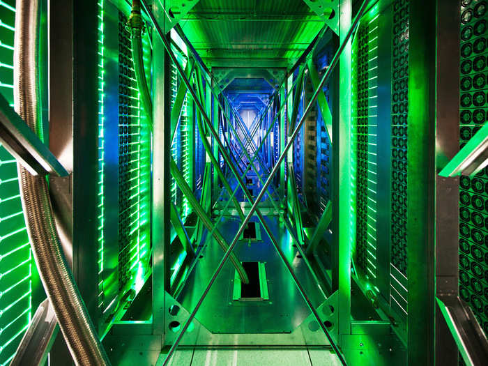 This is rare look behind the server aisle. Hundreds of fans can be seen taking hot air up and away from the racks, cooling it, and recycling the air back through.