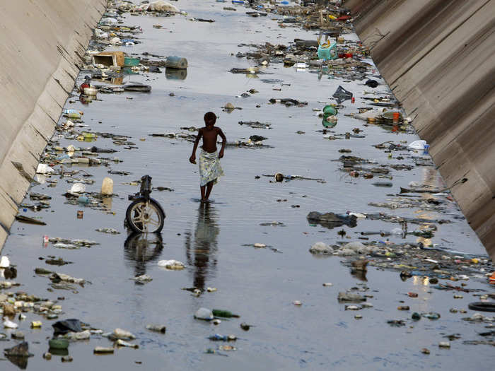 This boy strolls through a polluted canal in Benguela, Angola.