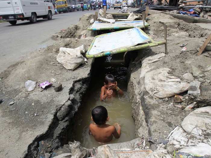 These boys splash around in an open drainage ditch in Manila, Philippines.