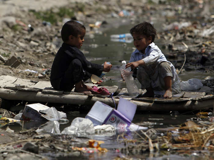 These boys balance over a murky puddle in Kabul, Afghanistan.