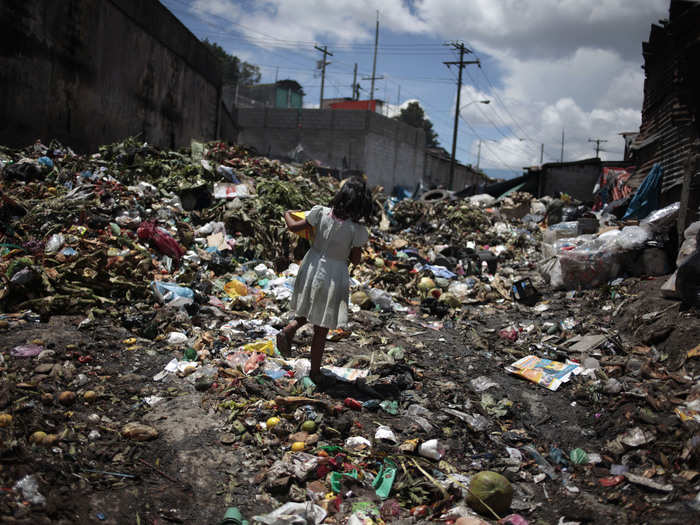 Just getting from one place to another can be difficult. This little girl walks through a sea of garbage produced by La Terminal food market in Guatemala City, Guatemala.