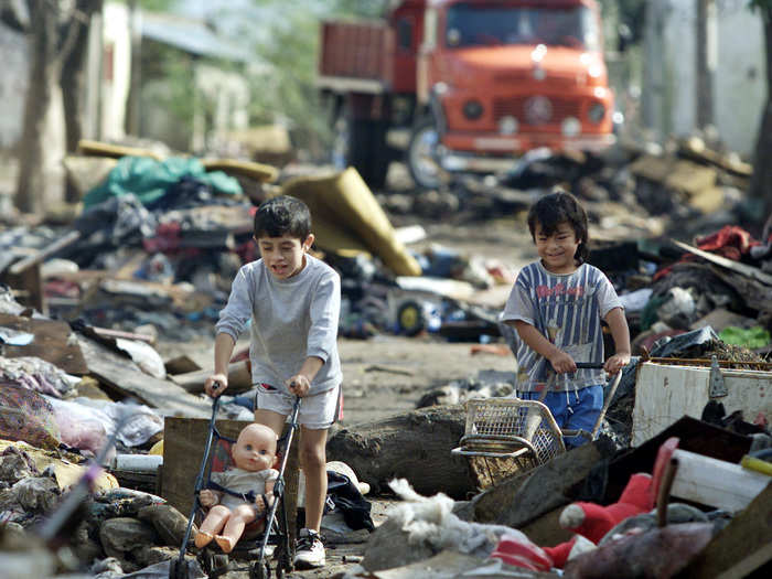 These boys navigate through heaps of rubbish on the streets of Santa Fe, Argentina.