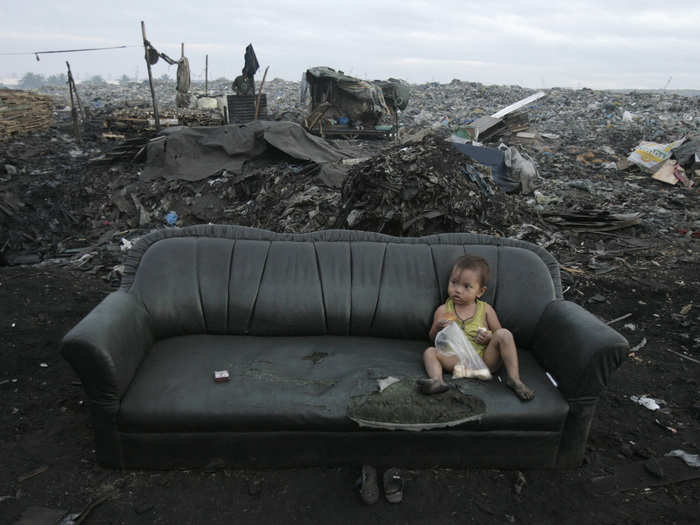 Many are accustomed to going about their day-to-day activities in contaminated environments. This child eats breakfast on a sofa in the middle of the a garbage dump in Tondo, Philippines.