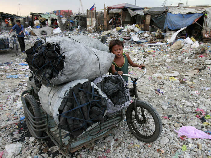 This boy pushes a cart full of charcoal, which was made at a garbage dump in Tondo, Philippines.