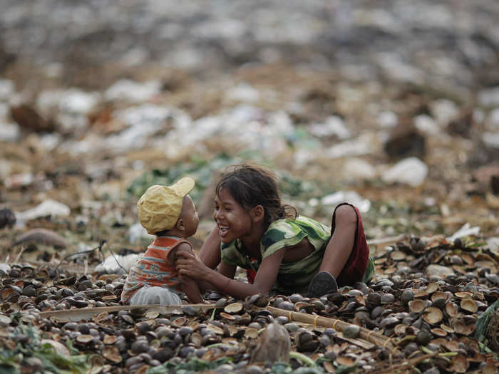 A little girl and her brother play in a junkyard outside of Yangon, Myanmar.