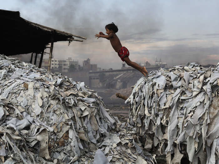 A girl jumps from one garbage heap to another at a tannery in Dhaka, Bangladesh. These waste products will be used to make feed for poultry, while the tannery — which doesn