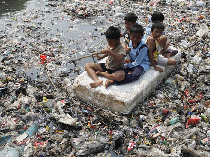 These children ride their makeshift raft down a river of garbage in Jakarta, Indonesia.